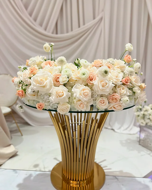 Blush rose and ranunculus centerpiece on a gold and glass table