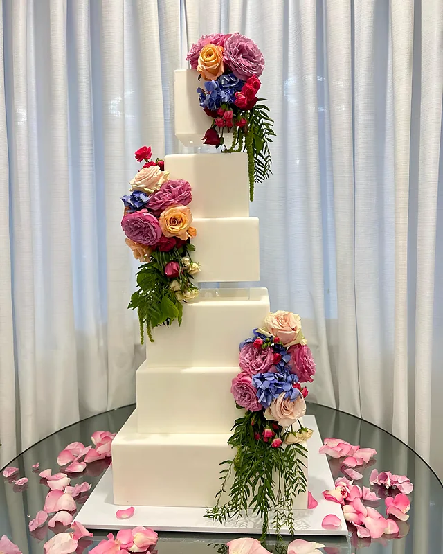 Tiered wedding cake decorated with a cascade of fresh flowers