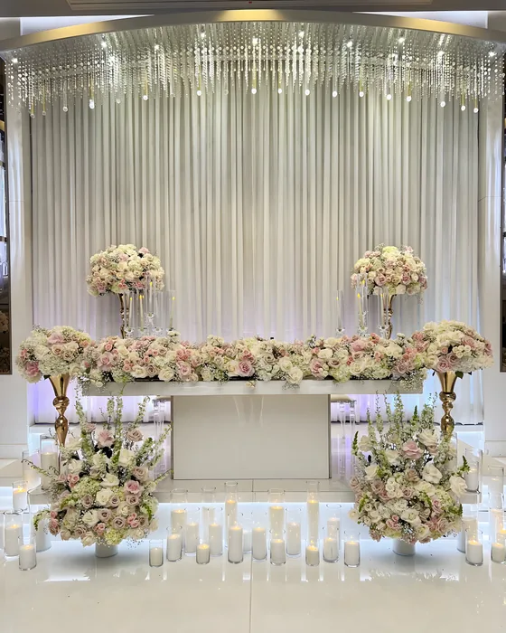 Wedding sweetheart table with blush floral garland, candles and draped crystal backdrop