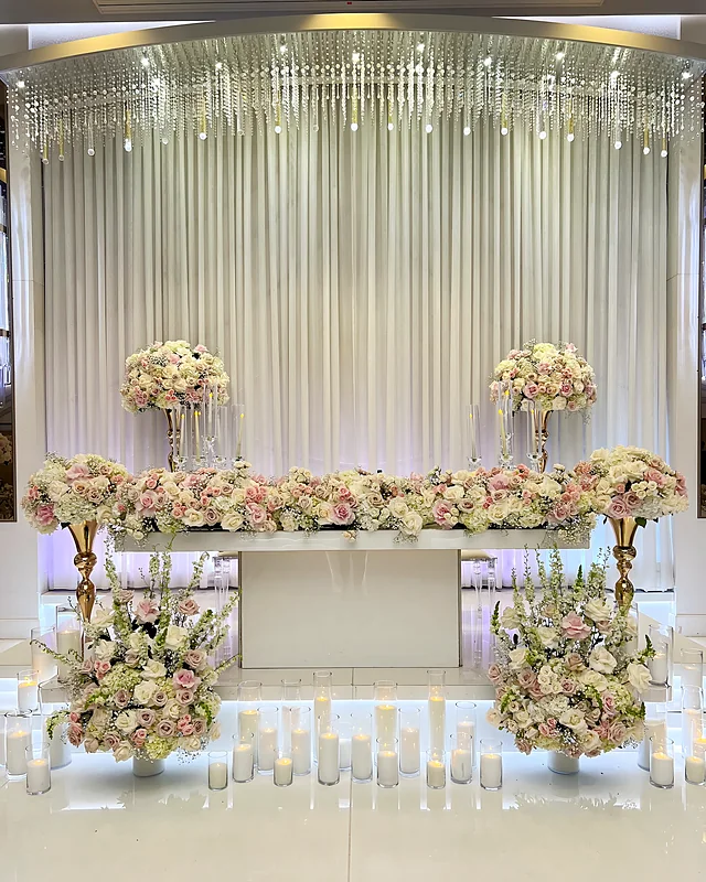 Wedding sweetheart table with blush floral garland, candles and draped crystal backdrop