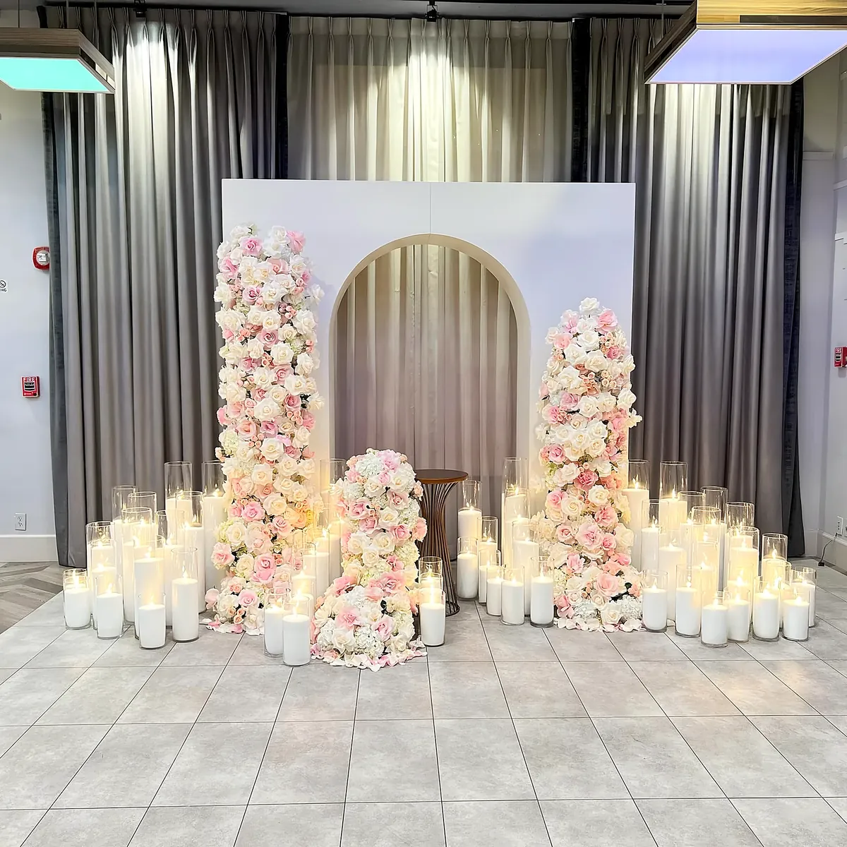 Rose-covered columns and an arch backdrop surrounded by white candles
